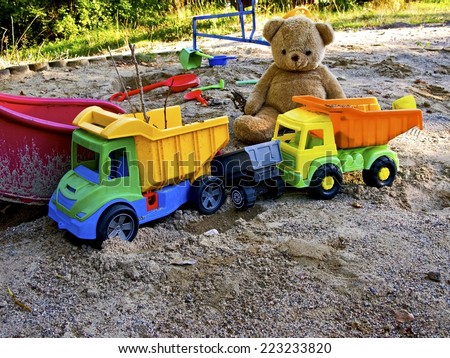Plastic toy vehicles and a teddy bear.