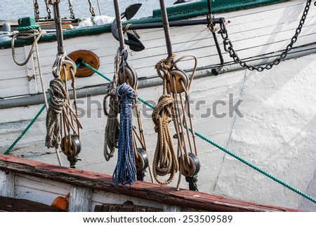 Part of sailing ship with pulleys and knotted ropes.