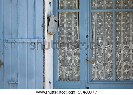 Blue door with lace curtain, blue shutter and brief case.
