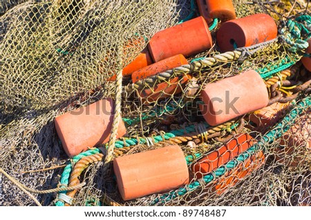 Heap of fishing net with ropes and red floats.
