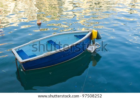 Small boat in front of house reflections in the water.