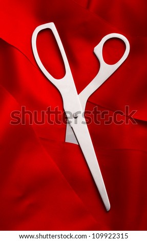 Top view of scissors cutting a red ribbon