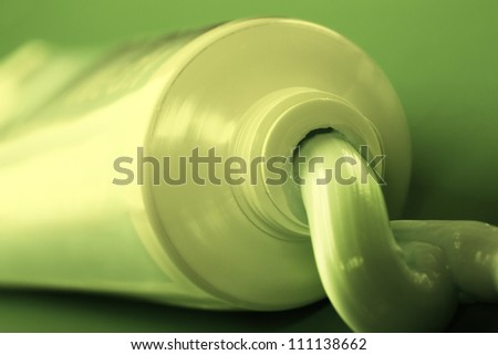 Herbal toothpaste squeezing out of tube. Toned in green