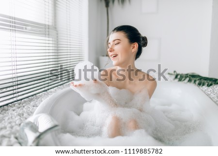 Woman sitting in bathtube and reads magazine