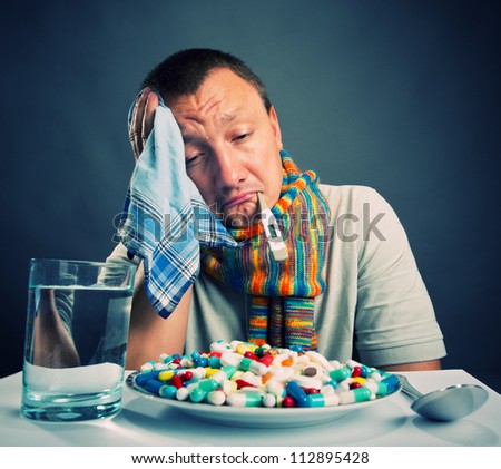 Sad ill man preparing to eat medicines