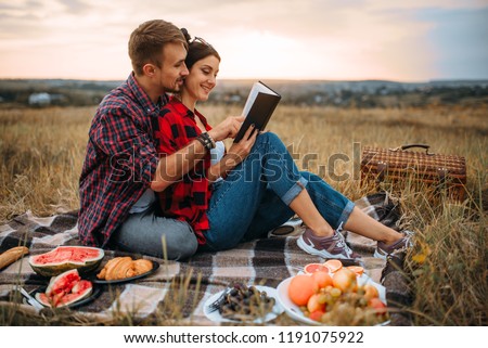 Couple reads book together, picnic on the grass
