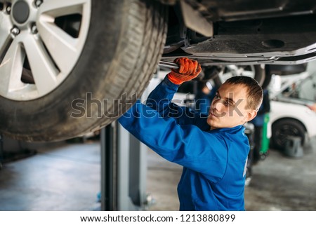 Mechanic repairs the suspension, car on the lift