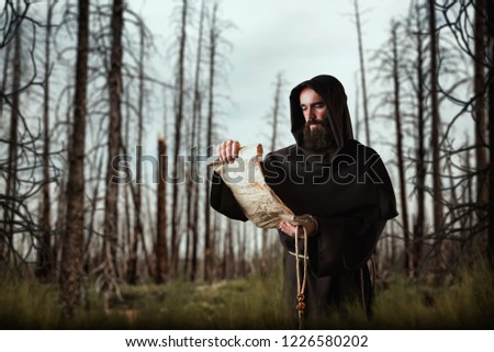 Medieval monk with an evil face reads a prayer