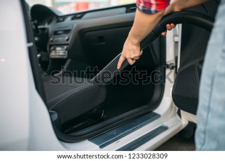 Woman cleans car interior with vacuum cleaner