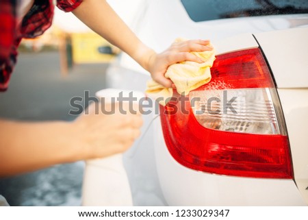 Woman cleans rear lights of the car with spray