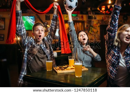 Football fans with scarf and ball in sports bar