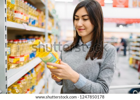 Woman choosing sunflower oil in a supermarket