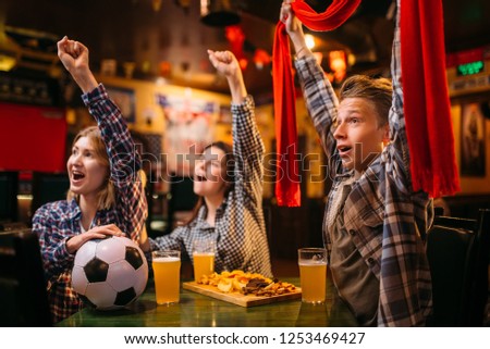 Football fans raise their hands up in sports bar