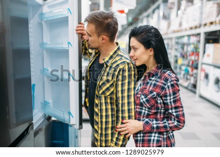 Young couple choosing refrigerator in supermarket