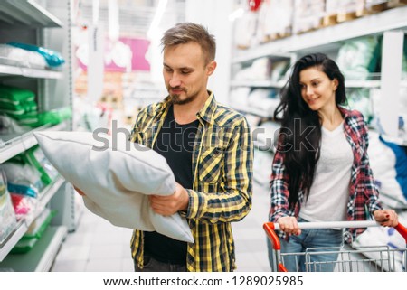 Happy couple buying pillow in supermarket
