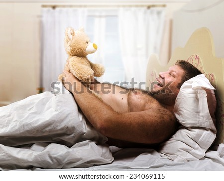 Adult man in bed looks at toy bear
