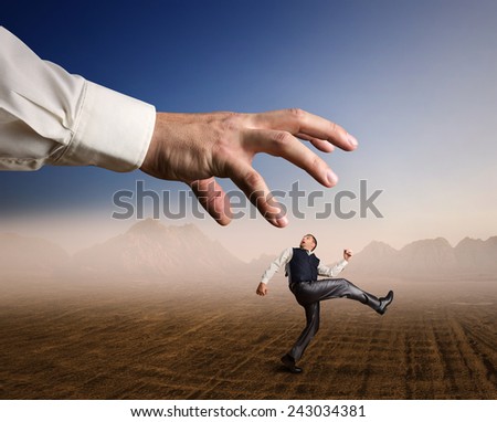 Businessman runs from a big arm