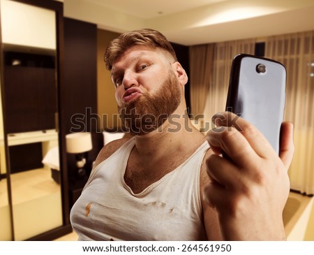 Fat glamour man takes selfie in bedroom