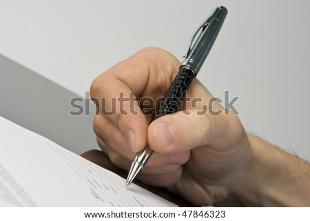 Man\'s hand signing the document