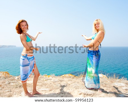 Two hot women in bikini and sarong inviting to sea