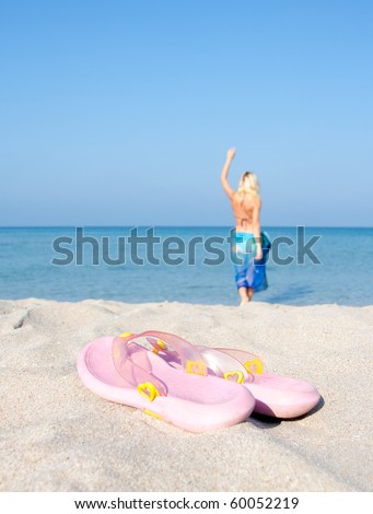 Flip flops on the beach with going for a swim woman on background