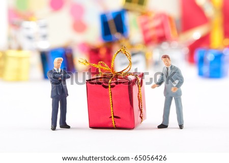Miniature figurines of two businessmen with red Christmas gift