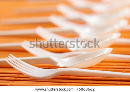 A row of plastic silverware. Spoons and forks