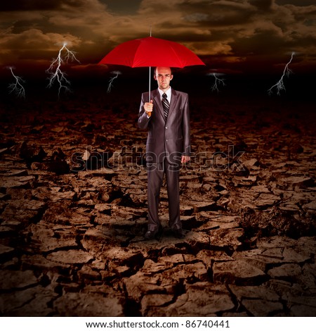 Business protection concept - Serious businessman with red umbrella against dramatic landscape