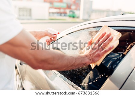 Male hand with tool for washing windows, car wash