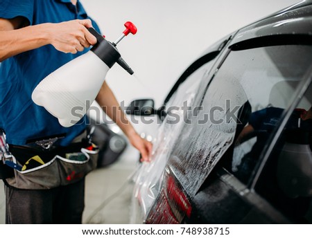 Male hand with spray, car window tint installation
