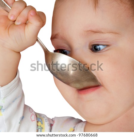 Baby girl holding spoon in mouth. Isolated on white
