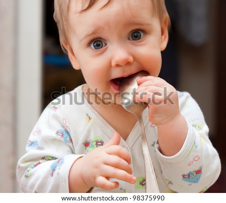 Portrait of shy baby girl holding spoon in mouth