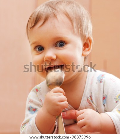 Portrait of happy baby girl holding spoon in mouth