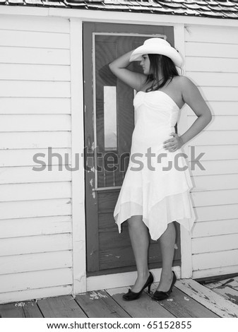Country girl on the back porch, dress and cowboy hat.