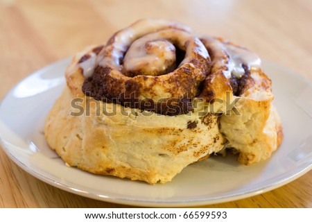 Fresh baked cinnamon roll iced and on white plate