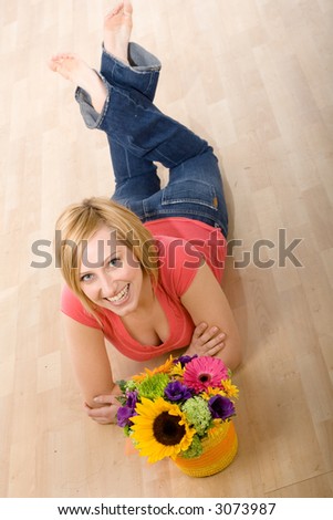Portrait of a beautiful young woman with a bouquet of colorful flowers laying on the floor.