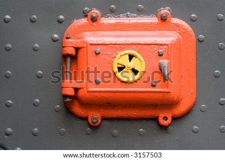 A bright red metal hatch bolted into a gray metal background