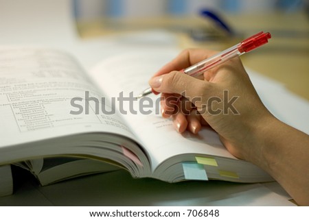 open book with hand and red pen, soft focus