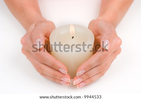Hands guarding a white candle over white
