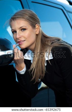 Businesswoman fix the make up, watching herself into the car mirror