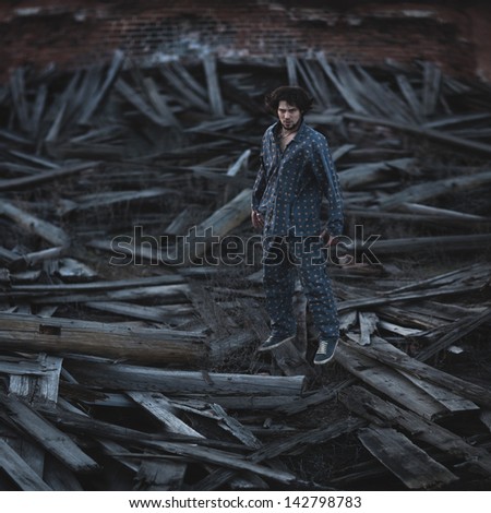 Young man in pajamas sleeping wandering through the old ruined building. Grain and textured added