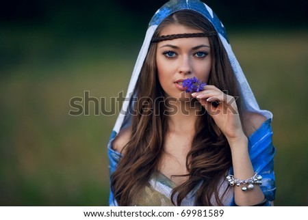 face of beautiful caucasian brunet woman with blue eyes and flower.