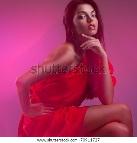 Fashion portrait of beautiful model wearing a cocktail red dress. Studio shot