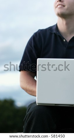 Young men, early evening, looks up from white laptop with a smile - casual dress