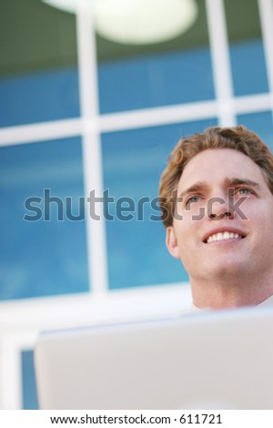 young businessman working on steps in front of building while looking ahead