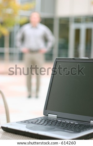 shot of laptop with man blurred in background