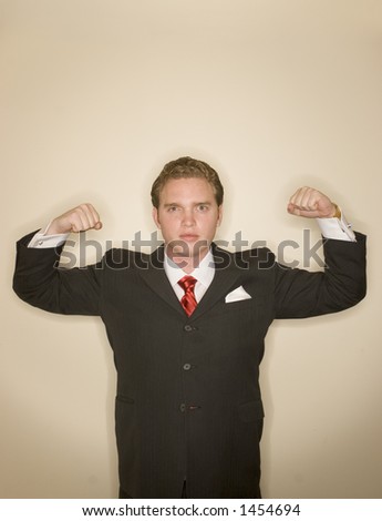 Business man in black suit, white shirt, and red tie is flexing his arms in power pose