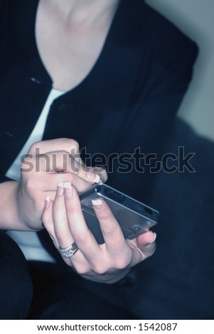 Business woman in black jacket and white shirt is holding and writing on her pda