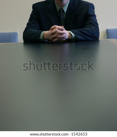 Man is holding his hands together on top of board room table