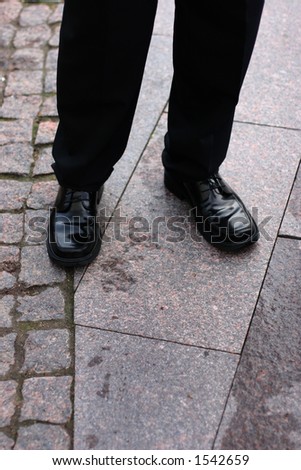 Black business shoes with some legs dressed in black slacks